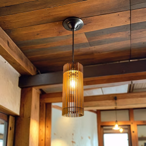 Cylinder-shaped wooden pendant light with vertical slats in a rustic wood-beamed interior.