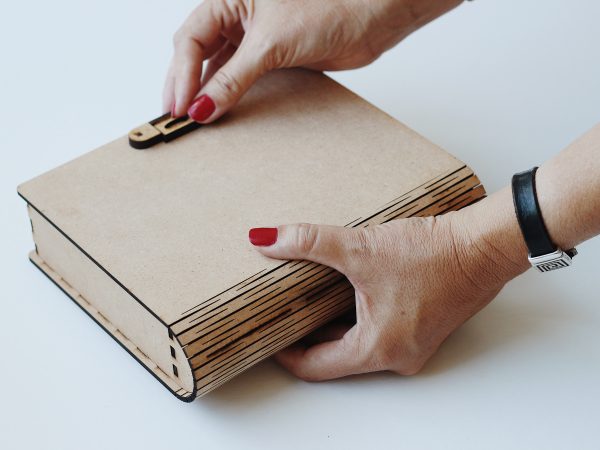 Hands opening a CNCPro laser-cut MDF gift box with curved edge and clasp